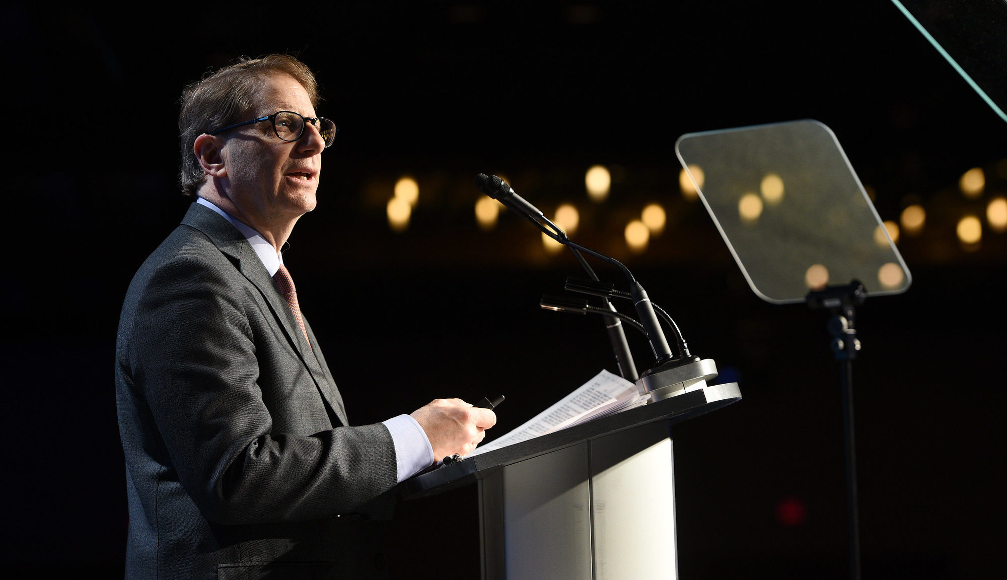 Edward Greenspon speaks at the podium against a darkened backdrop