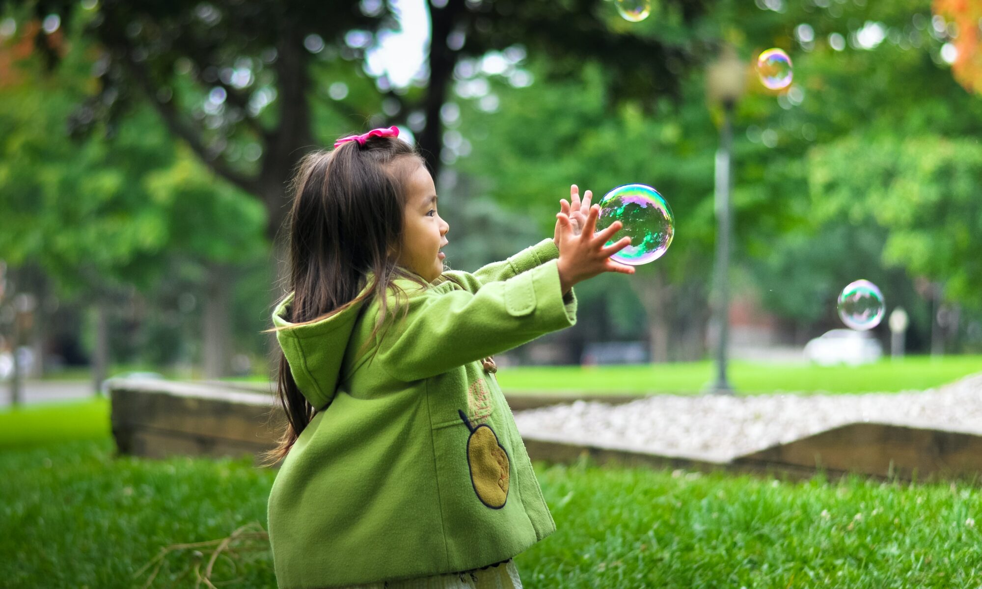 A young girl catching a bubble outside