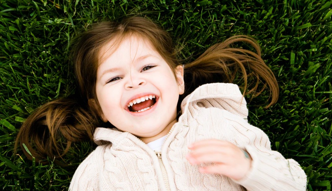 Girl laying on grass smiling