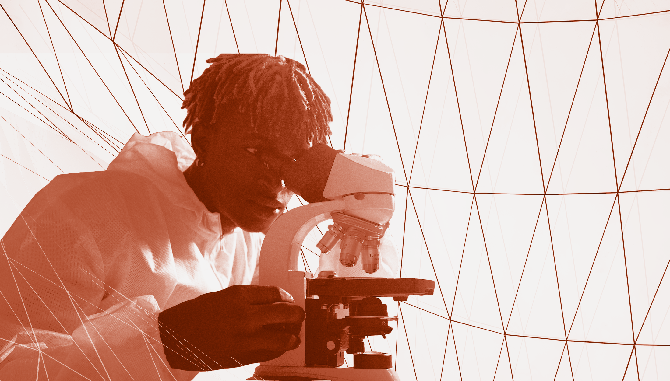 A black man looks through a microscope